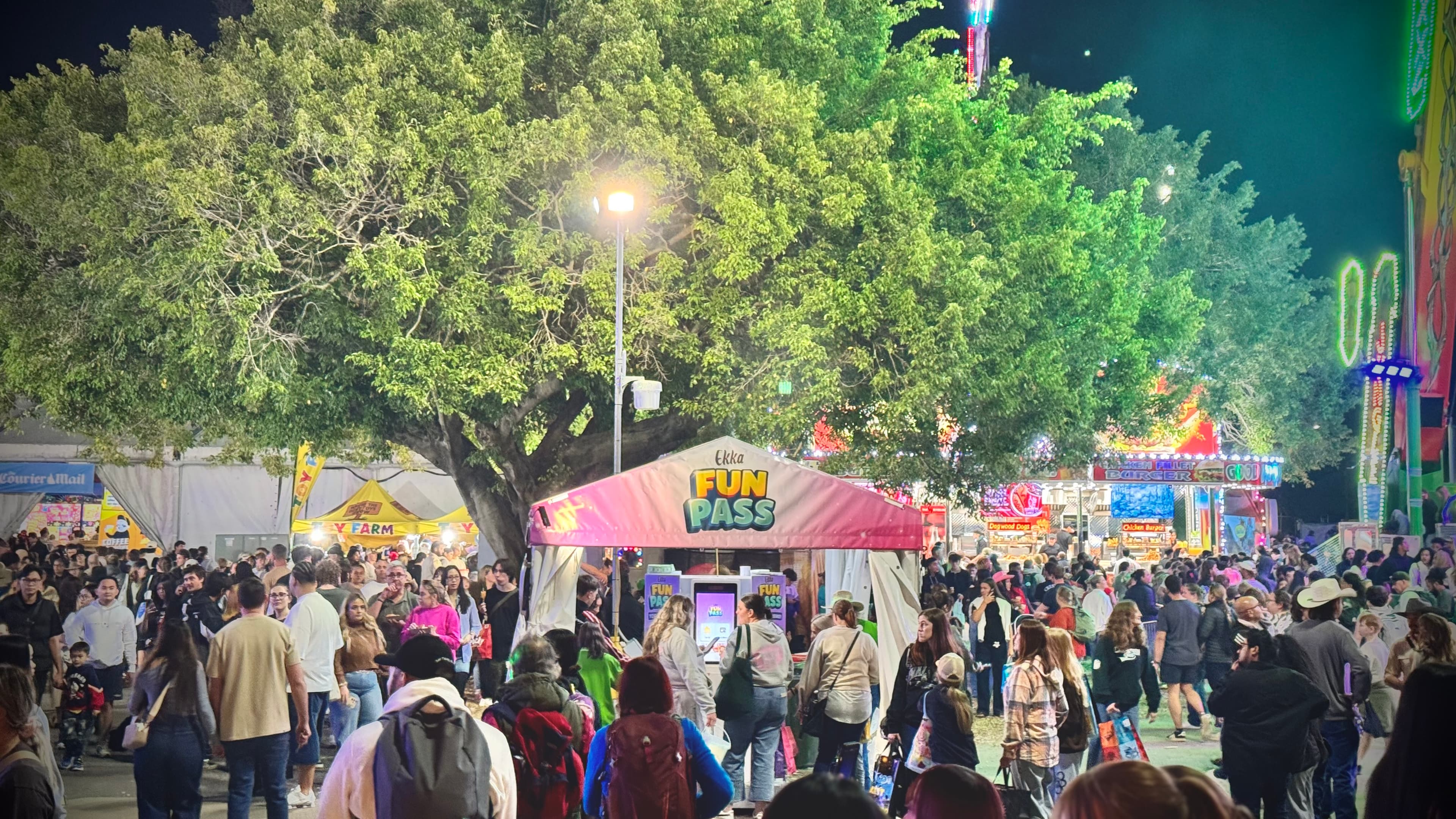 Ekka Fun Pass kiosk station at night — crowds navigating self-service top-up points across the showground